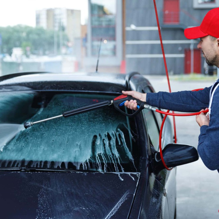 Professional car wash worker is washing client's car